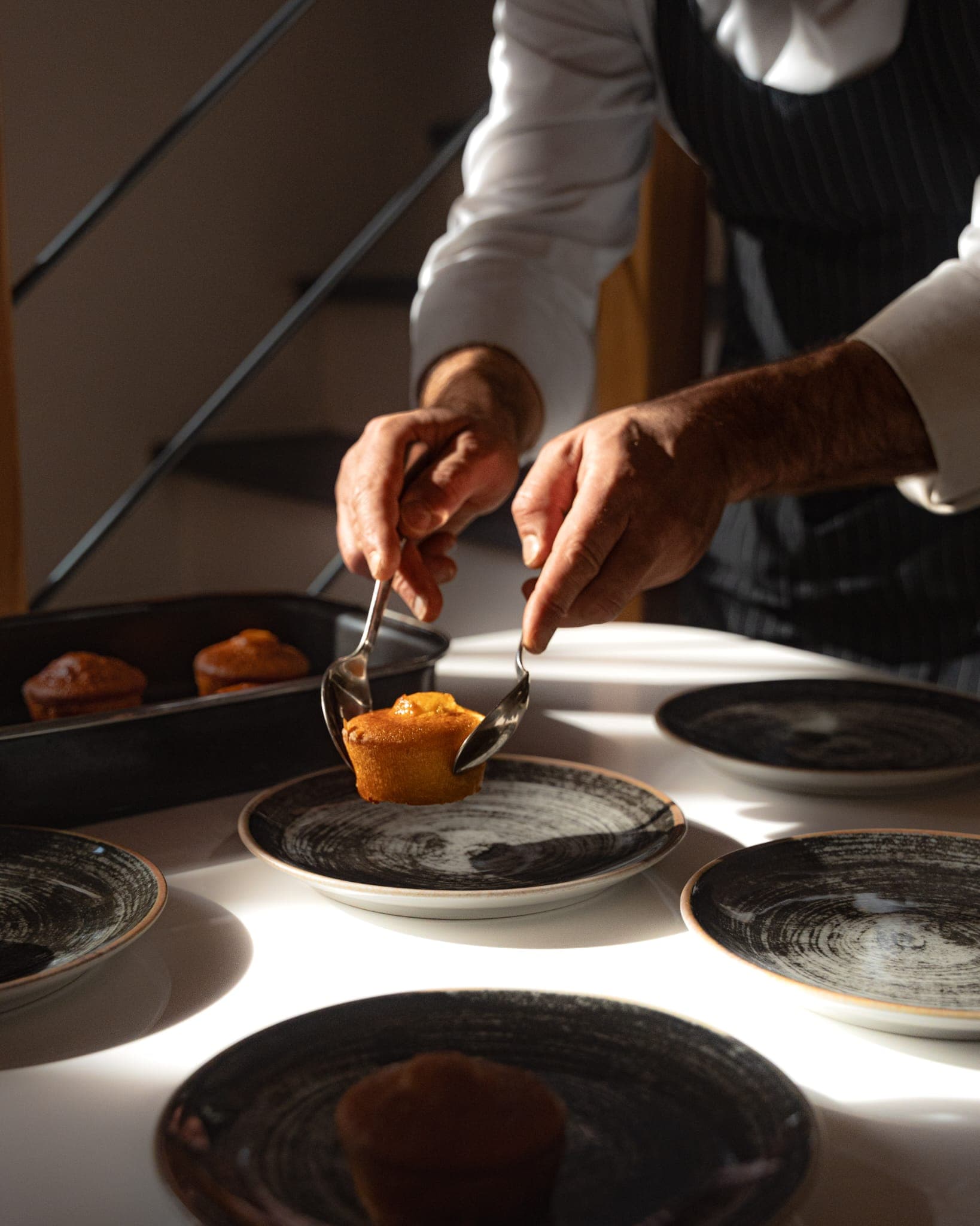 Lo chef rifinisce un dessert impiattato su piatti neri