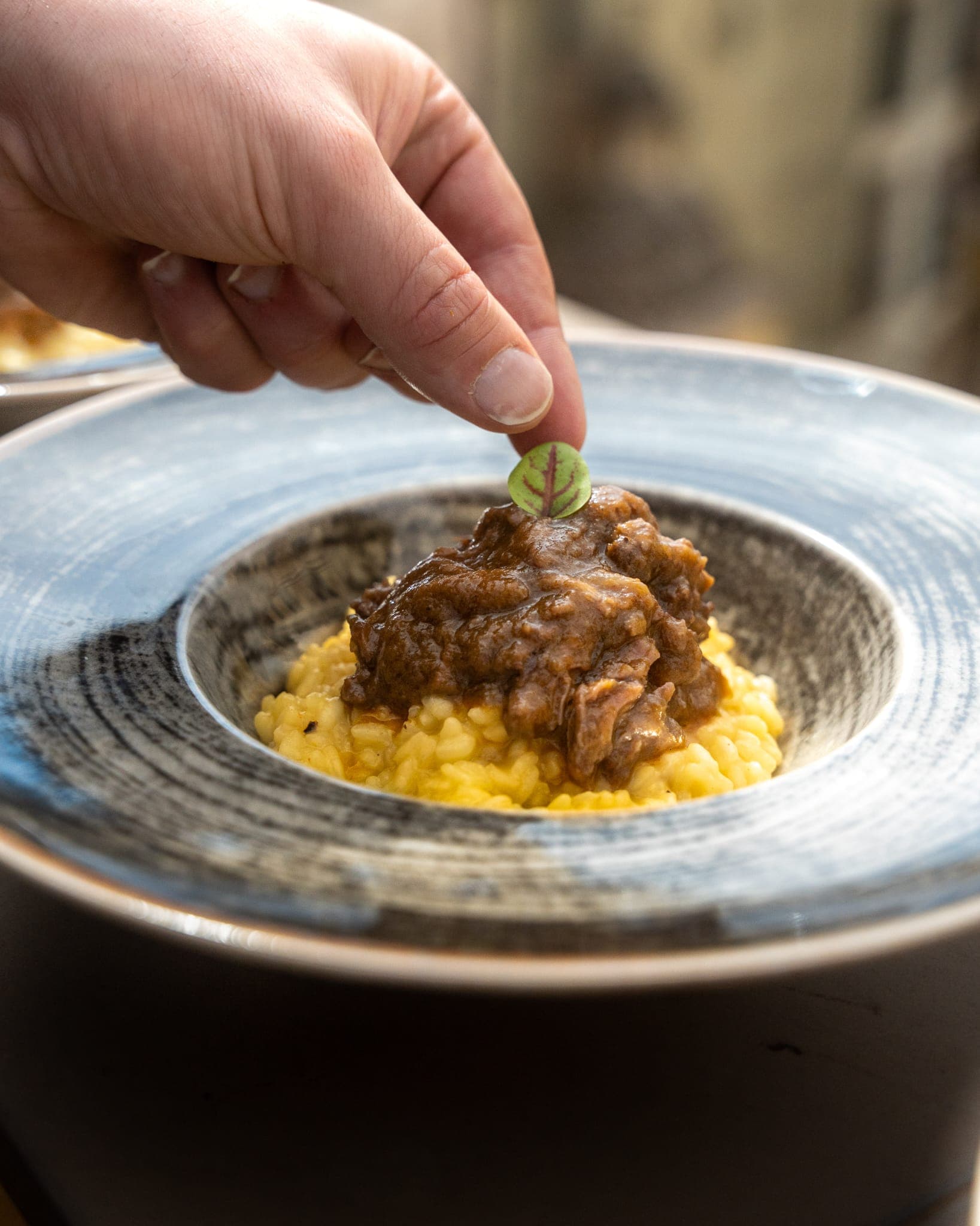 Lo chef completa l'impiattamento del risotto allo zafferano
